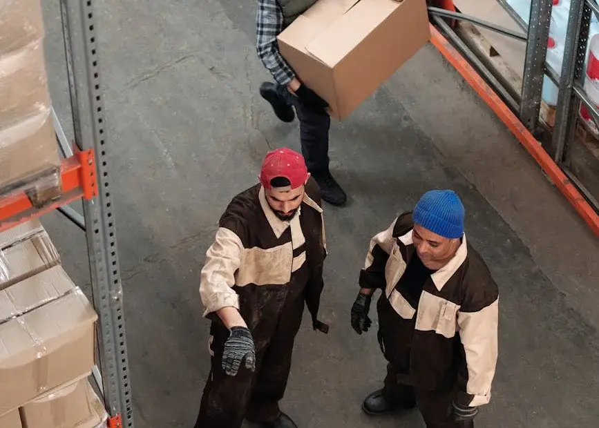 Team of workers managing inventory in a warehouse, emphasizing logistics and teamwork.