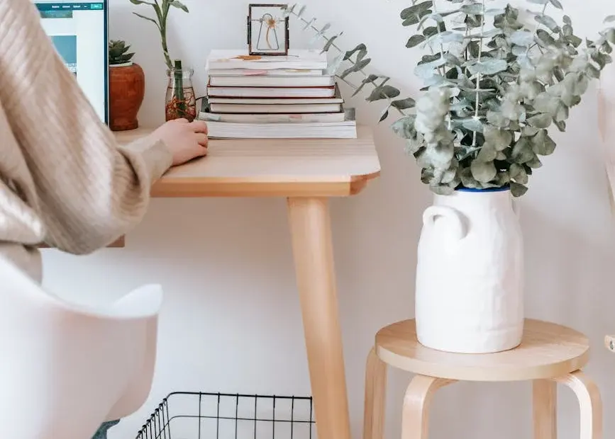 Cozy workspace with a laptop, books, and plants, promoting a relaxed, creative atmosphere.