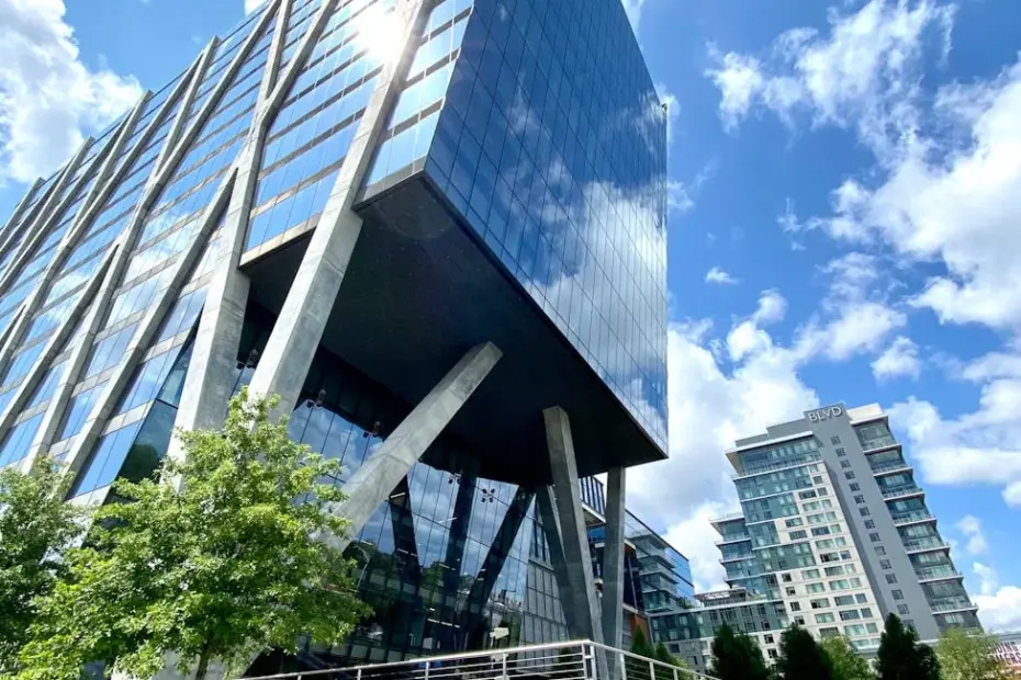 A sleek modern office building with glass facade, captured under a bright blue sky.
