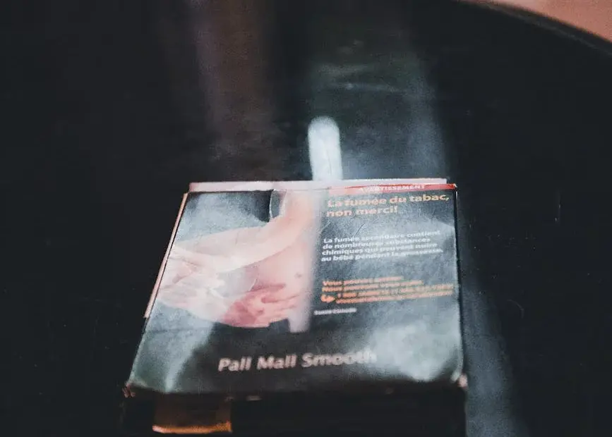 Close-up still life of a cigarette pack on a black table in a dimly lit room.