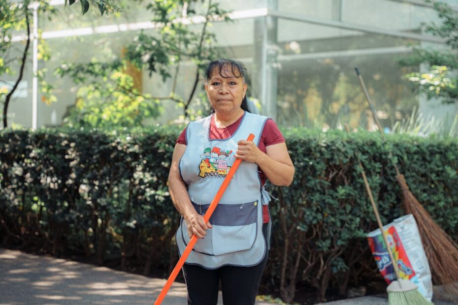 Woman cleaning outdoors with a broom in a city street during summer.