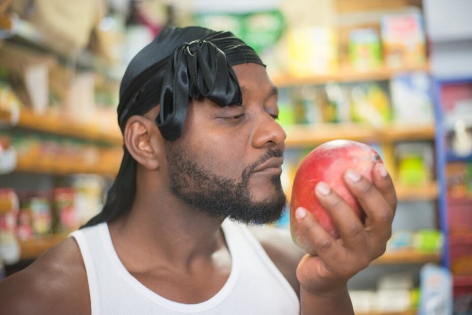 African American man smelling a fresh apple in a grocery store.