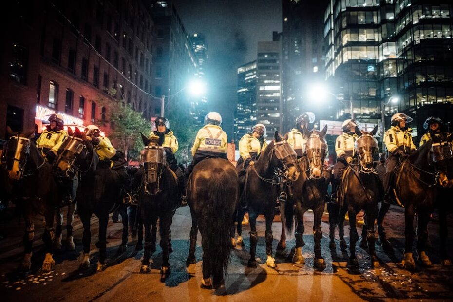 A line of mounted police officers in a city during a nighttime protest, maintaining order.