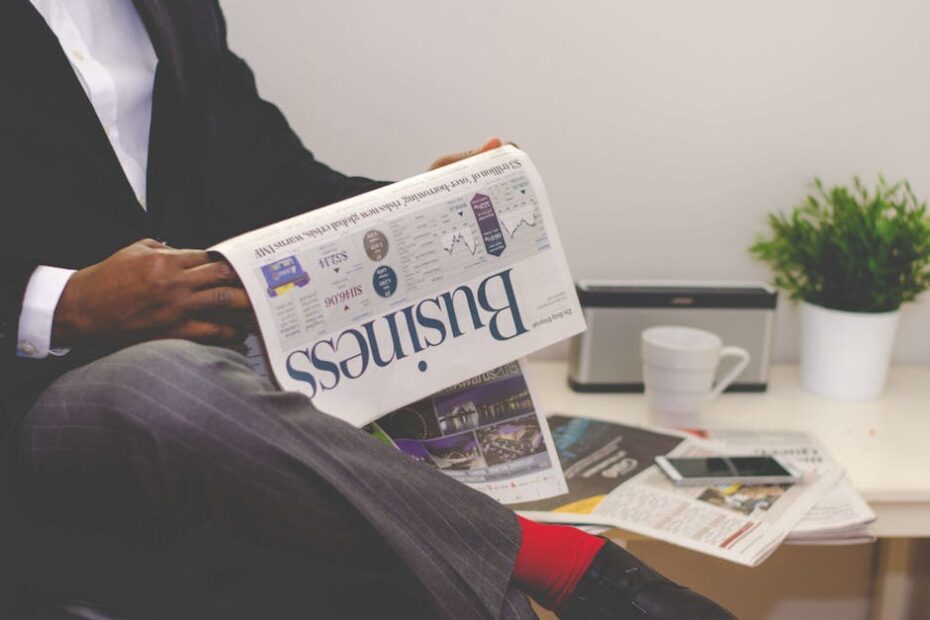 Businessman reading a financial newspaper at a desk, highlighting finance and commerce theme.